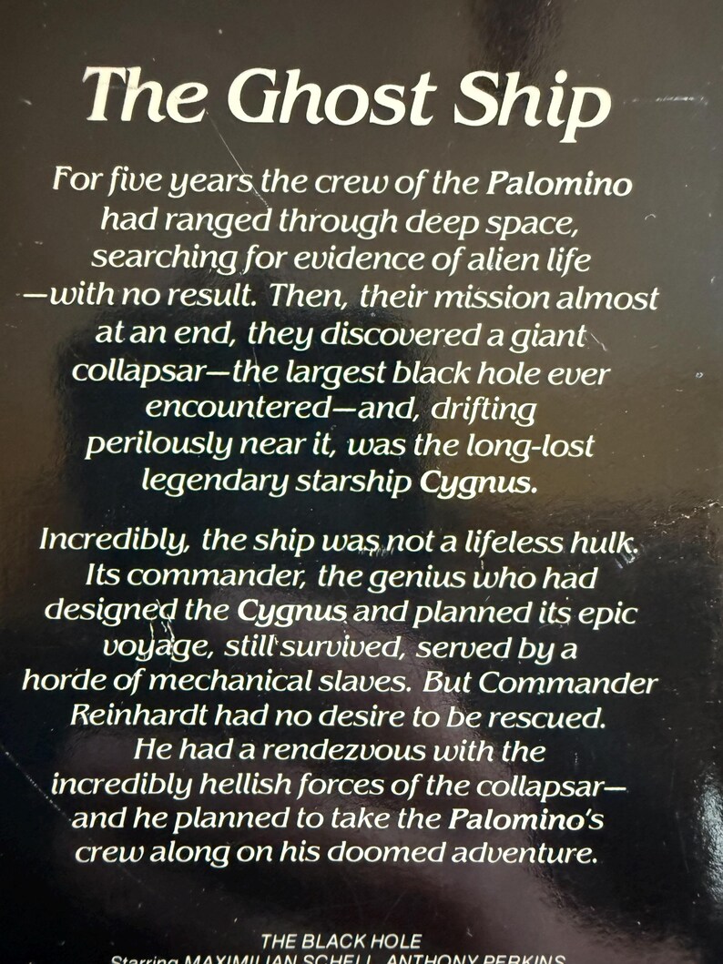 May include: A book cover with the title "The Ghost Ship" in white text. The text describes a space adventure involving a starship, a black hole, and a crew. The bottom of the cover lists the movie "The Black Hole" and the actors.