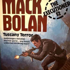 May include: Vintage paperback book cover for "Mack Bolan: Tuscany Terror." The cover features a man aiming a gun with a muzzle flash. Bold text reads "MACK BOLAN" and "THE EXECUTIONER 52."