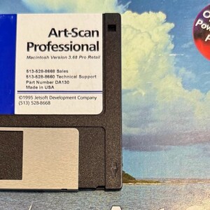 May include: A black 3.5-inch floppy disk with a white label featuring the text "Art-Scan Professional" and other details. A blue rectangle is on the top left of the label. A sticker in the upper right corner reads "Optimized for PowerMac and Pentium."