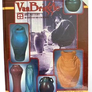 May include: A hardcover book titled "The Collector's Encyclopedia of Van Briggle Art Pottery." The cover features images of various pottery pieces in shades of blue, orange, and brown, along with a black and white photo of a potter.