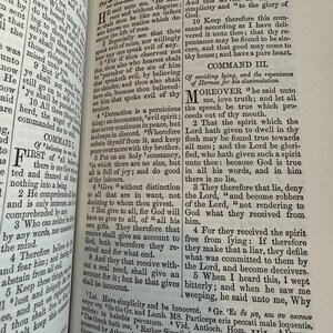 May include: An open book displaying biblical text, with headings "COMMAND II" and "COMMAND III". The pages are aged, and the text is printed in black. The book is open to a specific passage, showing the text.