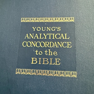 May include: A close-up of a dark blue book cover with gold lettering and decorative borders. The text reads "YOUNG'S ANALYTICAL CONCORDANCE to the BIBLE". The book appears to be a religious reference.