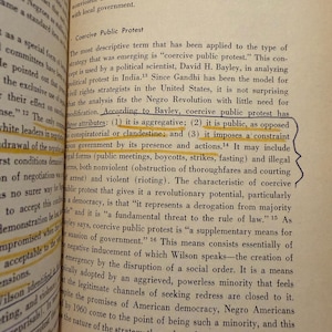 Op de afbeelding: Open boekpagina met tekst over "Coercive Public Protest" en zijn kenmerken. De tekst is in zwarte letters op verouderd, vergeeld papier. Het boek heet "The Strategy of Protest".