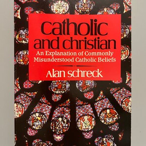 May include: Book cover with a red background and the title "Catholic and Christian: An Explanation of Commonly Misunderstood Catholic Beliefs" by Alan Schreck. The cover features a stained glass window with red, blue, and yellow colors.