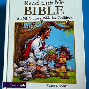 May include: A hardcover children's Bible titled "Read with Me BIBLE." The cover features a colorful illustration of Jesus and a child, with birds in a tree. The book is published by Zonderkidz and is a revised and updated edition.