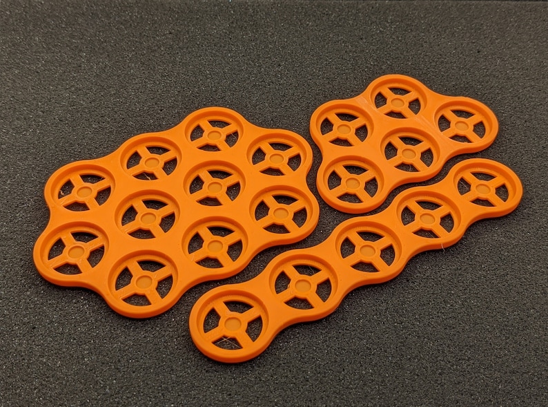 May include: Three orange plastic trays with circular compartments. The trays are designed to hold small items, such as coins or beads.