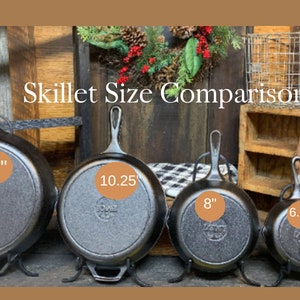 May include: A size comparison of five cast iron skillets. The skillets are arranged from largest to smallest, with the largest skillet measuring 12 inches in diameter and the smallest skillet measuring 3.5 inches in diameter. The skillets are all black and have a rustic look.