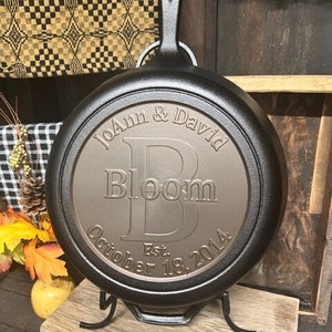 May include: Black cast iron skillet with a handle, personalized with the text "JoAnn & David Bloom Est. October 18, 2014".