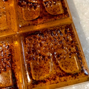 Pode incluir: Um close-up de uma barra de sab&atilde;o com uma cor marrom e laranja. O sab&atilde;o tem um design de &aacute;rvore em relevo.