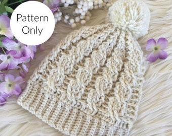 May include: A crocheted beanie hat in a cream color with a fluffy white pom pom on top. The hat has a cable knit pattern and a folded brim. The text "Pattern Only" is visible in the image.