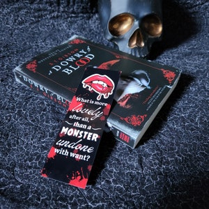 Può includere: Un segnalibro nero e rosso con il testo "What is more lovely after all, than a MONSTER undone with want?"  Il segnalibro presenta una bocca rossa aperta con i denti.