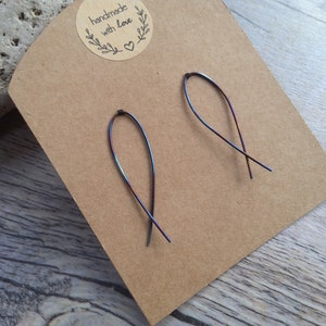 May include: A pair of iridescent wire earrings with a simple, curved design. The earrings are displayed on a brown card with the text "handmade with love".