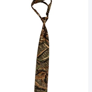 May include: A camouflage-patterned tie in shades of brown, green, and beige. The tie is knotted at the top, with the wider end hanging down. The fabric appears to be a standard tie material.