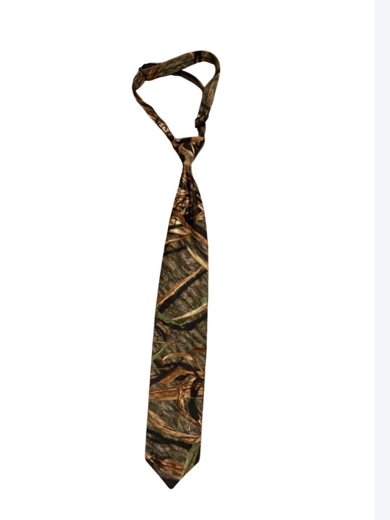 May include: A camouflage-patterned tie in shades of brown, green, and beige. The tie is knotted at the top, with the wider end hanging down. The fabric appears to be a standard tie material.