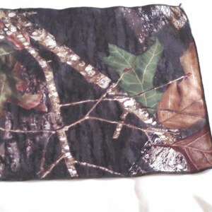 Puede incluir: Una tela de camuflaje con fondo negro y hojas y ramas marrones, verdes y blancas.