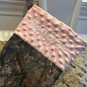 May include: A pink and brown camouflage Christmas stocking with the name "Sawyer" embroidered on the pink cuff.