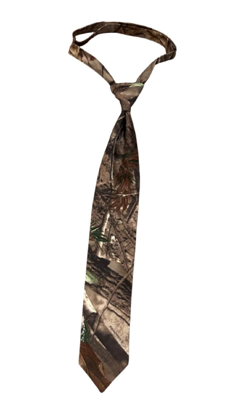May include: A camouflage-patterned tie, with a knot and a long, pointed end. The tie features a mix of brown, green, and tan hues, creating a woodland camouflage design. The tie is designed for formal or semi-formal wear.