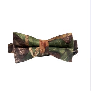 Puede incluir: Una pajarita de camuflaje con estampado marr&oacute;n, verde y naranja.