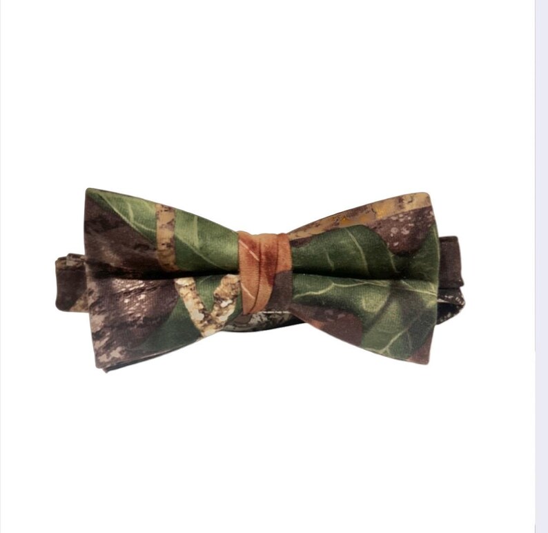 Puede incluir: Una pajarita de camuflaje con estampado marr&oacute;n, verde y naranja.