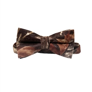 Puede incluir: Una pajarita marr&oacute;n con un estampado de camuflaje con hojas marrones, beige y blancas.
