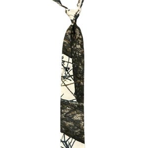 May include: A patterned tie with a camouflage design. The tie features a mix of white, black, and brown tree branch designs. The tie is knotted and hangs against a white background.