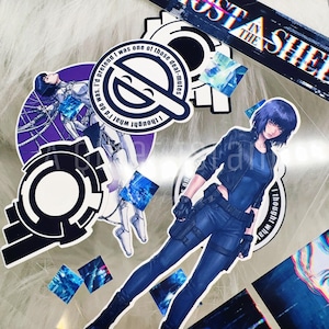 May include: A collection of anime-style stickers featuring characters and text from the "Ghost in the Shell" series. The stickers include images of a woman in a blue outfit, gear-shaped designs, and text that reads "Ghost in the Shell".