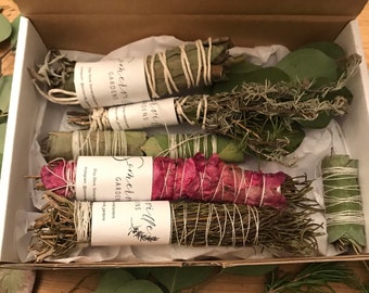Può includere: Una scatola di sei bastoncini di incenso fatti a mano, avvolti in spago ed etichettati "Somerville Gardens". I bastoncini di incenso sono fatti con varie erbe e fiori, tra cui rosmarino, eucalipto e petali di rosa.