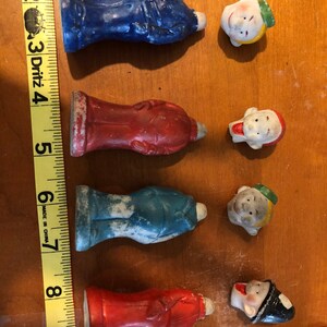 Może przedstawiać: Zestaw ośmiu ceramicznych figurek, cztery figurki w całości i cztery głowy. Figurki są pomalowane na czerwono, niebiesko i biało. Głowy są pomalowane na biało, czerwono i żółto. Figurki mają około 5 cm wysokości.