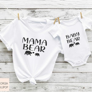 May include: White t-shirt with the text "Mama Bear" and two black bear silhouettes. A white baby bodysuit with the text "Baby Bear" and two black bear silhouettes.