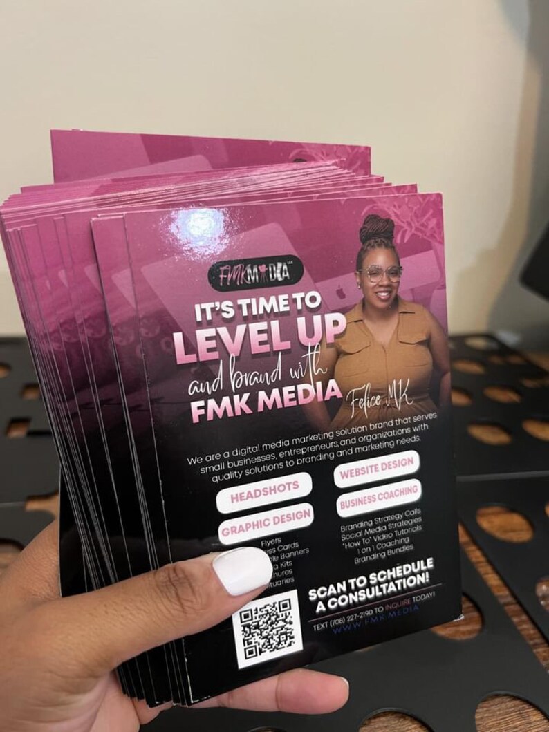 May include: A stack of rectangular marketing flyers with a dark pink and black colour scheme. The text reads IT'S TIME TO LEVEL UP and brand with FMK MEDIA. It features a photo of a person, a QR code, and a list of services including headshots, website design, graphic design, and business coaching.