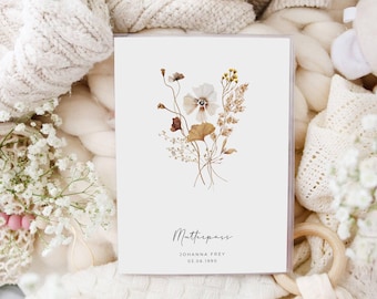 May include: A white card with a floral design and the text "Mutterpass" in cursive. Below the floral design is the text "JOHANNA FREY 03.06.1990".