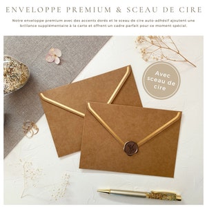 May include: Two brown envelopes with gold accents and a wax seal. The envelopes are on a white surface with a small bouquet of white flowers and a pen.