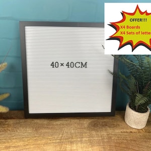 May include: Black framed letter board with white letters, measuring 40 x 40 cm. The board is sitting on a wooden surface.