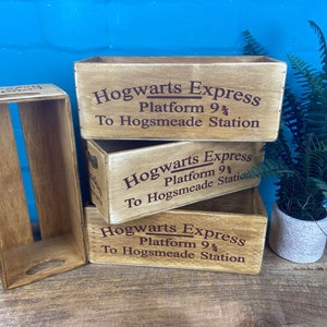 May include: Three wooden crates stacked on top of each other. Each crate is painted brown and has the words "Hogwarts Express" printed on the front in black. The text also includes "Platform 9 3/4" and "To Hogsmeade Station".