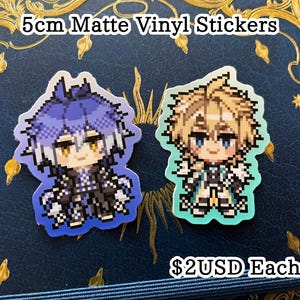 May include: Two 5cm matte vinyl stickers featuring pixelated anime-style characters. One has blue hair and the other has blonde hair. The stickers are on a dark blue surface with gold decorative accents.