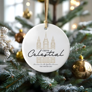 May include: White ceramic ornament with a gold outline of a temple and the text "Think Celestial" in black script. Below the temple is the text "Families Can Be Together Forever" and "THE SMITHS 2023".