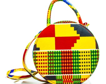 May include: A round, yellow, red, green and black patterned handbag with a single strap.