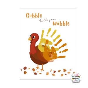 May include: A Thanksgiving-themed printable art print featuring a cartoon turkey with a handprint tail. The text "Gobble till you Wobble" is written above the turkey. The turkey is surrounded by orange and brown leaves.