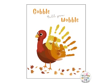 May include: A Thanksgiving-themed printable art print featuring a cartoon turkey with a handprint tail. The text "Gobble till you Wobble" is written above the turkey. The turkey is surrounded by orange and brown leaves.