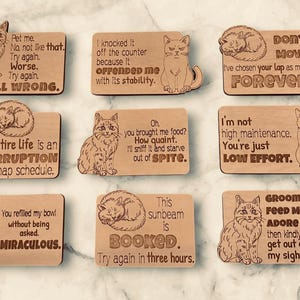 Nine wooden cat magnets with humorous sayings.
