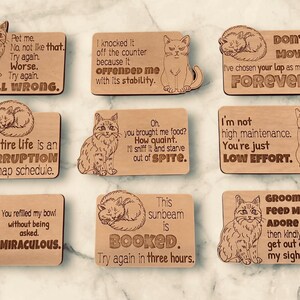 Nine wooden cat magnets with various cat illustrations and humorous sayings.