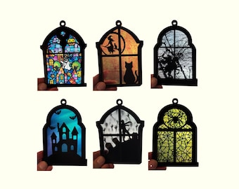 Pode incluir: Seis ornamentos com moldura preta em arco apresentando vários designs: uma cena de abóbora em estilo vitral colorido, uma bruxa numa vassoura com um gato, um cavaleiro sem cabeça, uma casa assombrada com morcegos, um cemitério com zombies e um padrão de teia de aranha.