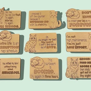 Nine wooden cat magnets with humorous sayings.