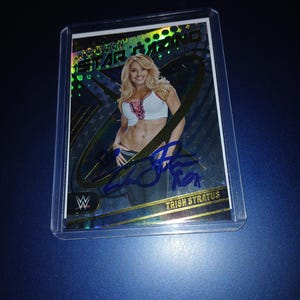 Può includere: Una carta da collezione di wrestling con Trish Stratus, una wrestler. La carta è in uno schema di colori oro e blu con una finitura olografica. La carta ha una firma in inchiostro blu. La carta è in una custodia protettiva di plastica.