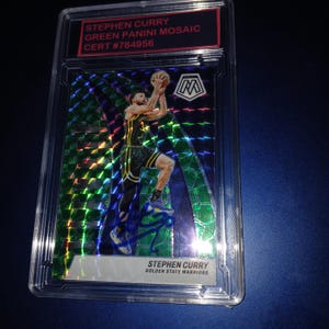 Puede incluir: Una tarjeta coleccionable Stephen Curry Green Panini Mosaic en una funda protectora. La tarjeta presenta un diseño de mosaico con un jugador de baloncesto en acción. La tarjeta está calificada y certificada con un número de identificación único.