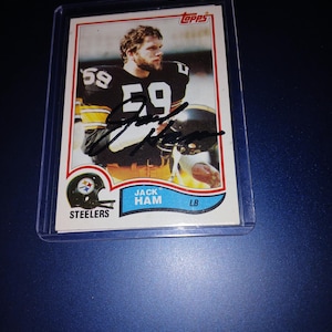 Op de afbeelding: Een Topps-verzamelkaart met Jack Ham, een linebacker van de Pittsburgh Steelers. De kaart is uit de jaren 1970 en toont een foto van Ham in zijn uniform, terwijl hij een voetbal vasthoudt. De kaart bevat ook Hams naam, positie en team.