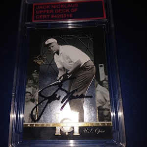 Op de afbeelding: Een Jack Nicklaus Upper Deck SP trading card, in een beschermende houder. De kaart toont een zwart-wit afbeelding van Nicklaus in een golfhouding, met zijn handtekening. De bovenkant van de kaart heeft de tekst "JACK NICKLAUS UPPER DECK SP CERT #420316".