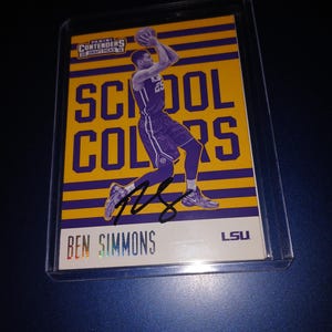 May include: A basketball trading card featuring Ben Simmons of the LSU Tigers. The card is yellow and purple with the text "School Colors" and "LSU".