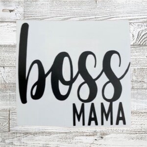 May include: Black and white vinyl decal with the text "boss mama" in a cursive font.
