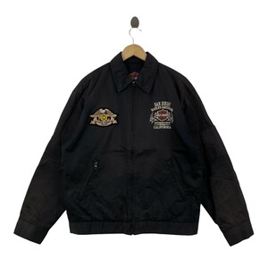 May include: A black zip-up jacket featuring a collar and long sleeves. The chest displays an embroidered eagle patch with the text HOG and Harley-Davidson Group, alongside text reading San Diego Harley-Davidson Authorized Dealer California.